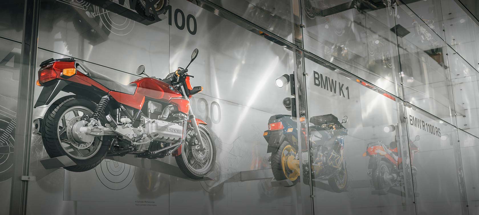 Wall installation of various BMW motorcycles like the BMW K 100 in red and the BMW K1 in blue as well as yellow in the BMW Museum