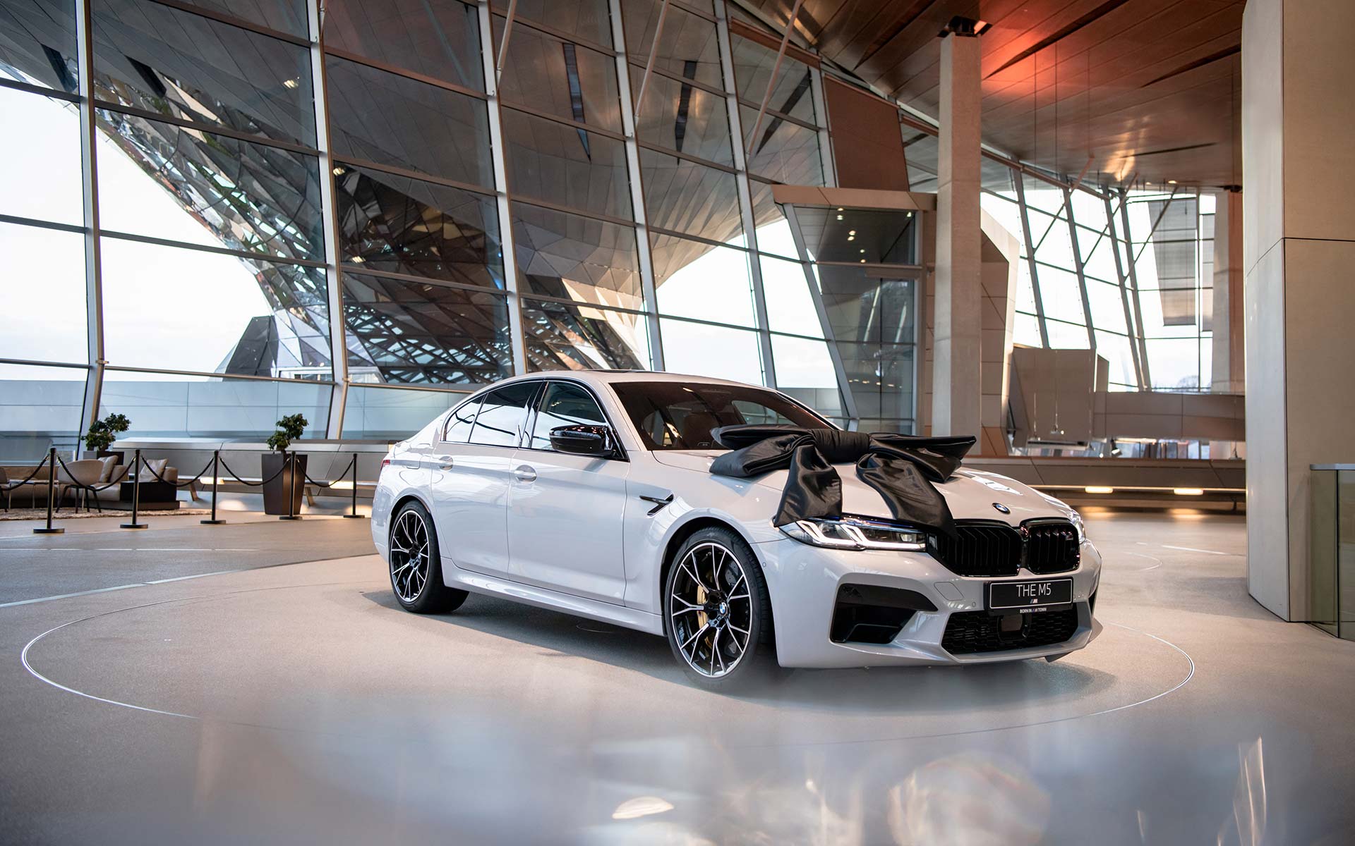 White BMW M5 with black bow on the pickup platform of BMW Welt