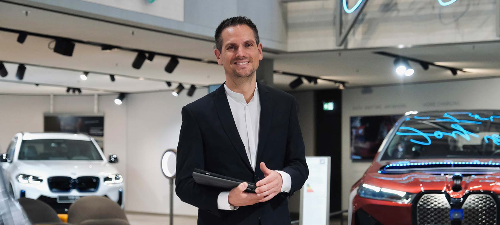 BMW Welt Consultation Smiling man in suit holds tablet for vehicle consultation at BMW Welt.