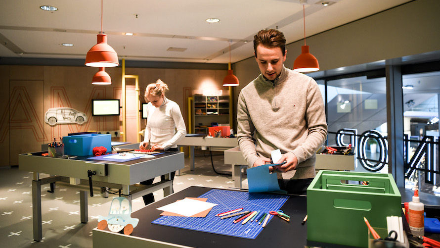 Two workshop participants work on their projects at work tables 