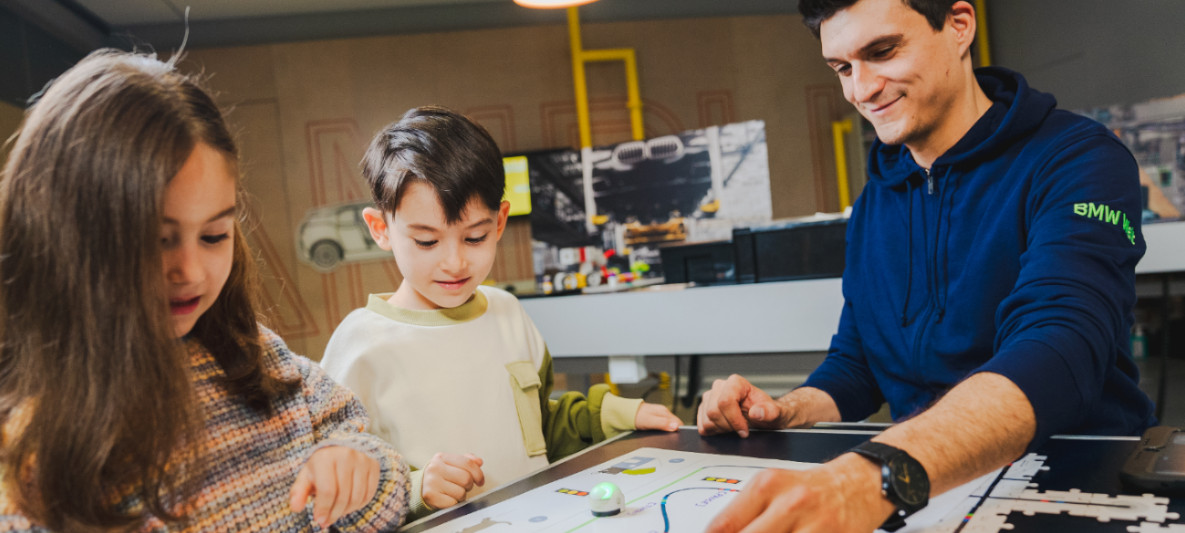 BMW Welt Workshop BMW Welt workshop leader explains to two children how circuits work using a child-friendly model