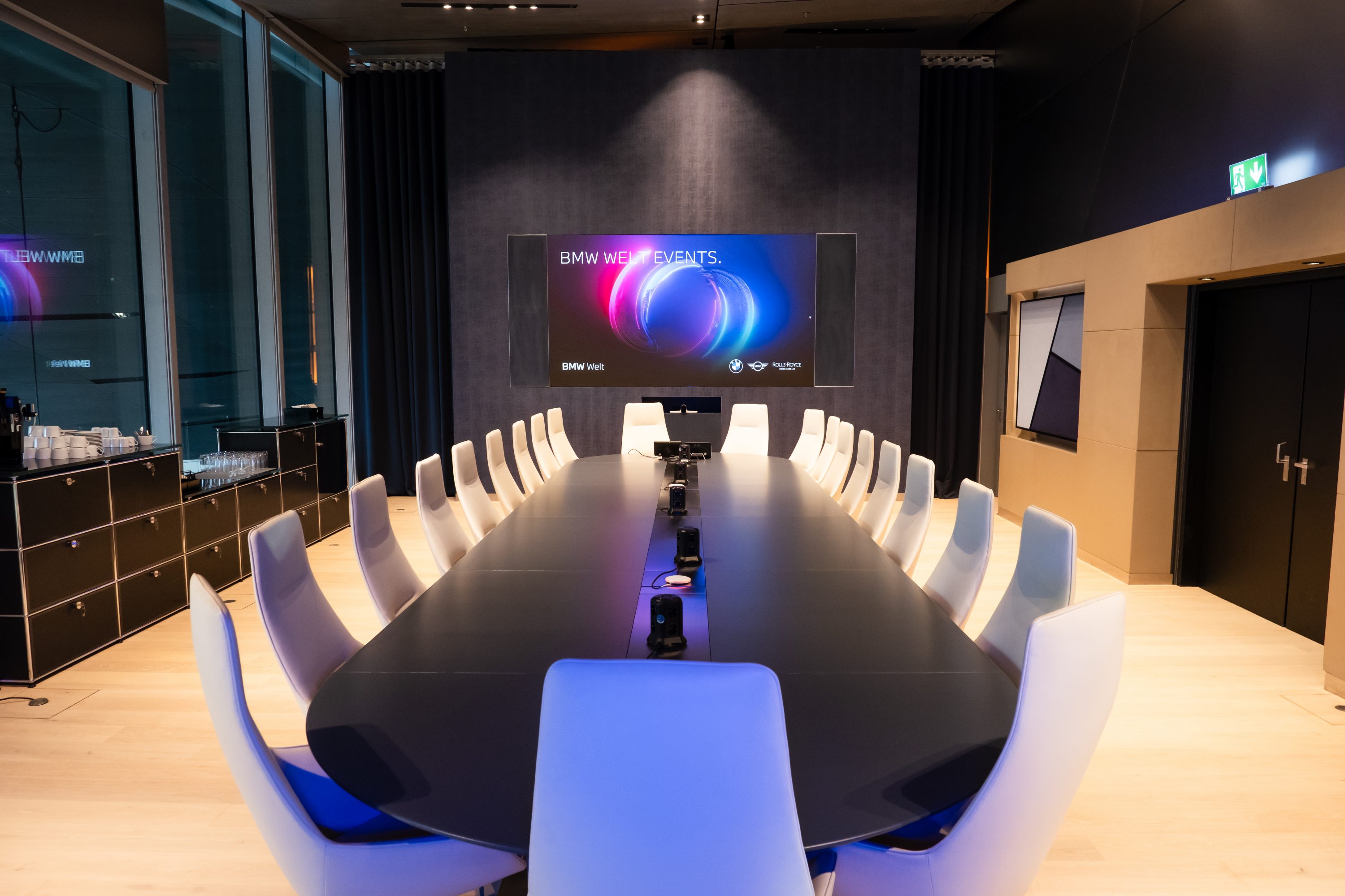 Blick in Konferenzraum mit großem Tisch und weißer Bestuhlung im Business Club der BMW Welt